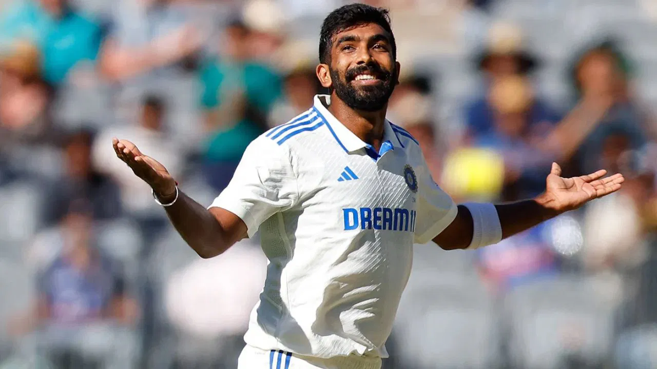 Jasprit Bumrah raising his hands in victory looking up at the sky with a cheerful smile